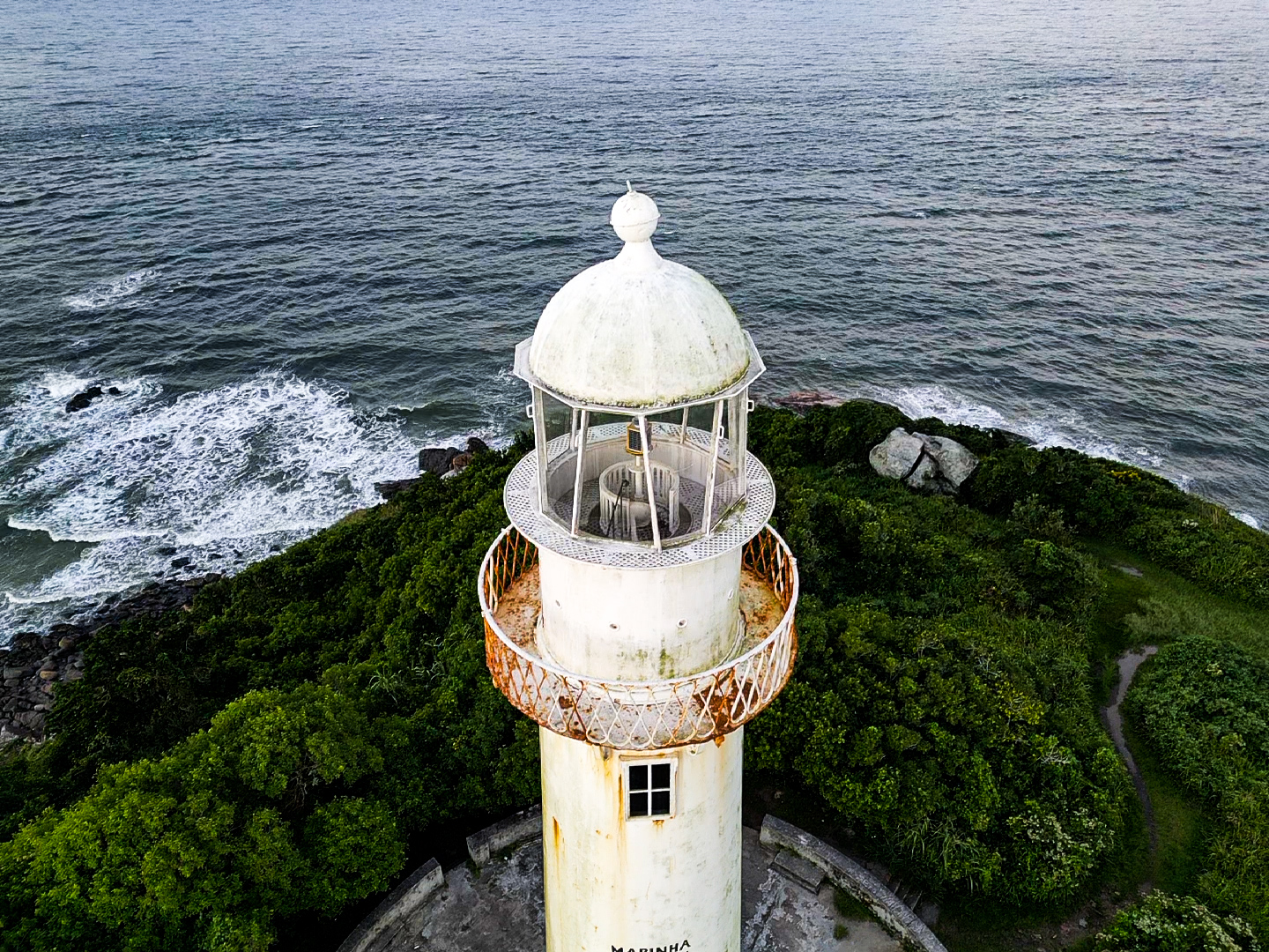 Detalhe aéreo do topo do Farol das Conchas, com o mar batendo nas pedras ao fundo